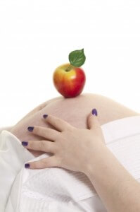 Pregnant woman with an apple resting on her belly